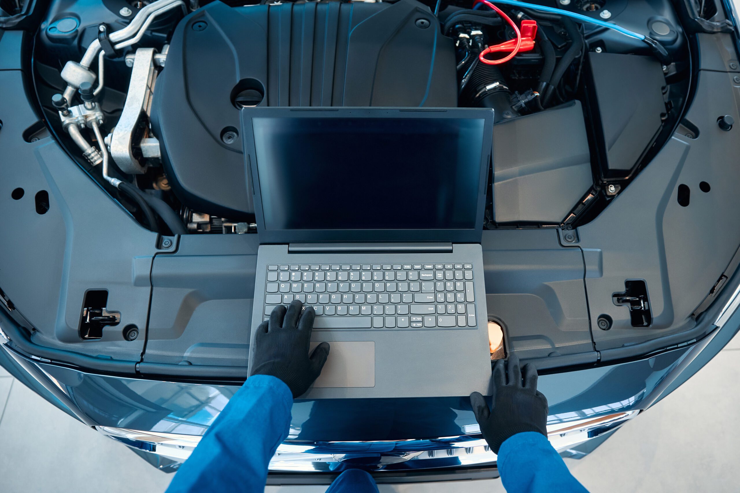 Car service, repair, maintenance concept - auto mechanic man or Smith writing to the clipboard at warehouse workshop, technician doing the checklist for repairs engine a car in the garage with laptop.